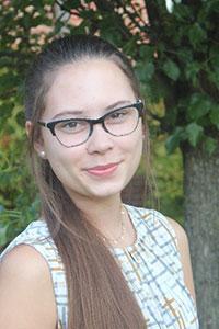 woman with long brown hair pulled into a ponytail wearing glasses and a light color pattern shirt