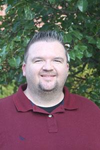 man with salt and pepper hair wearing a burgundy polo