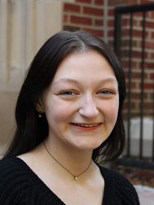 white woman with dark hair wearing a dark shirt sitting on steps